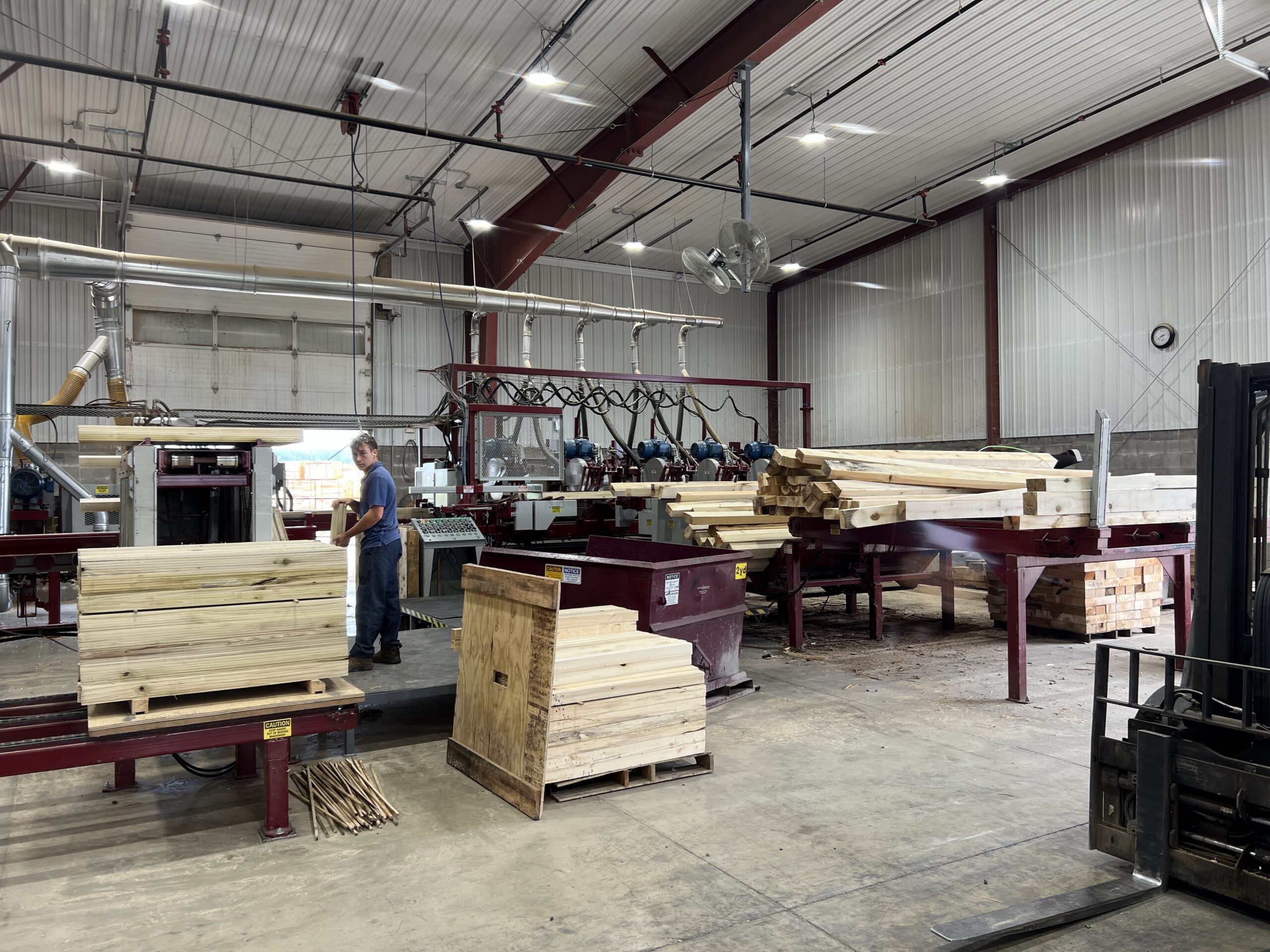 Troymill employee stacking freshly cut boards off the new saw line